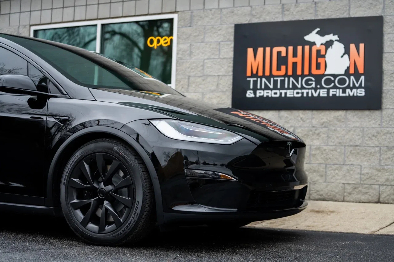 Black Tesla Model X beside the shop sign