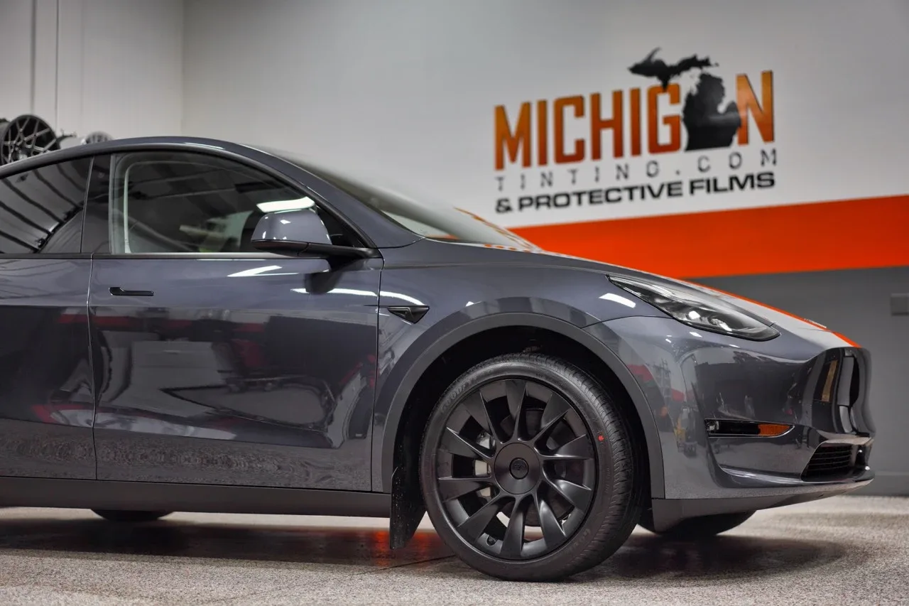 Grey Tesla Model Y beside the Michigan Tinting sign