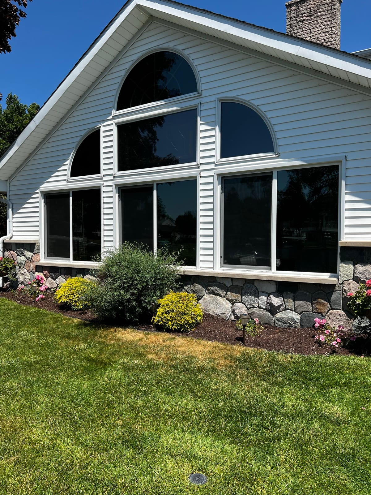White lake house with tinted arched windows
